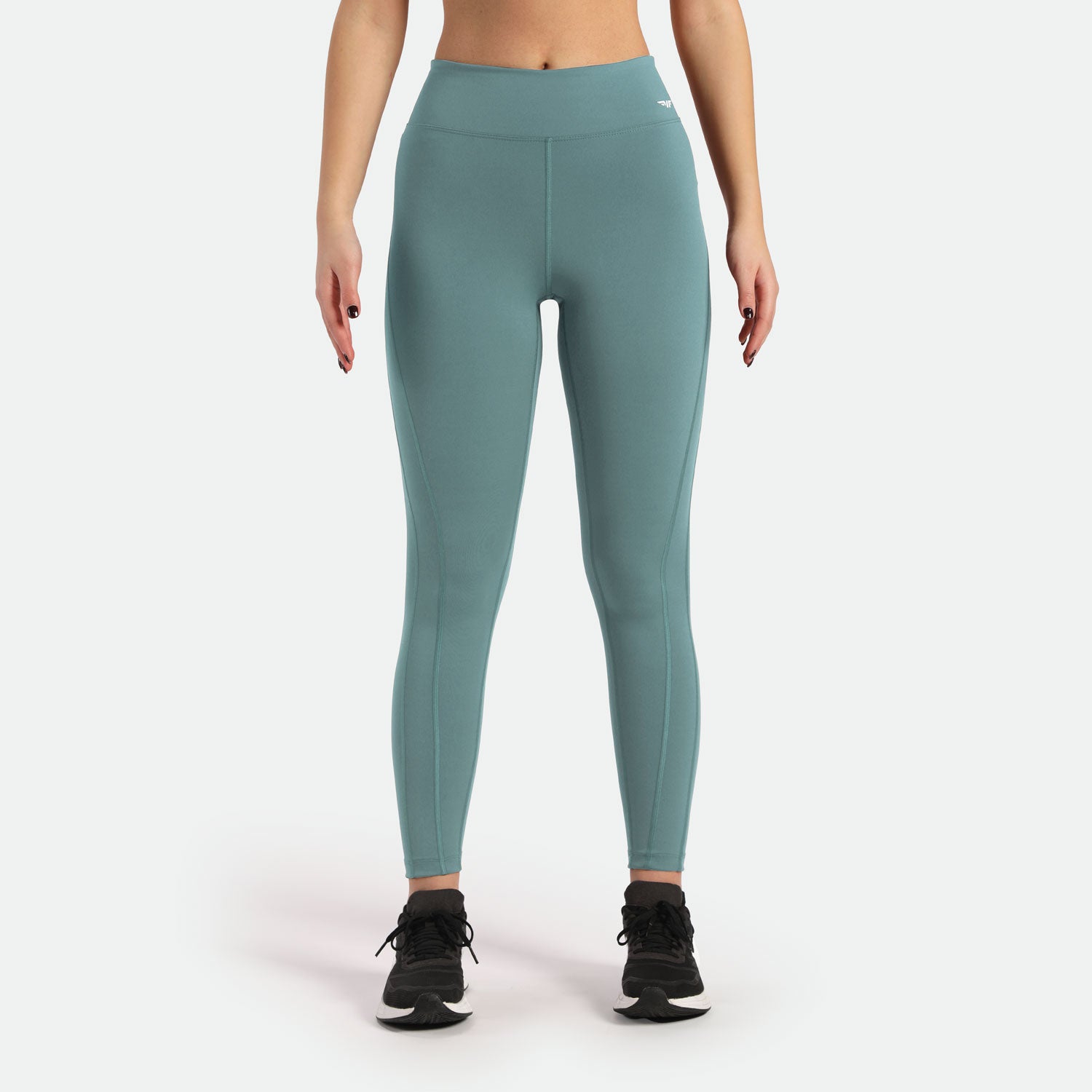 a fit woman wearing legging green with logo white on front ,shoes black ,the background is light grey