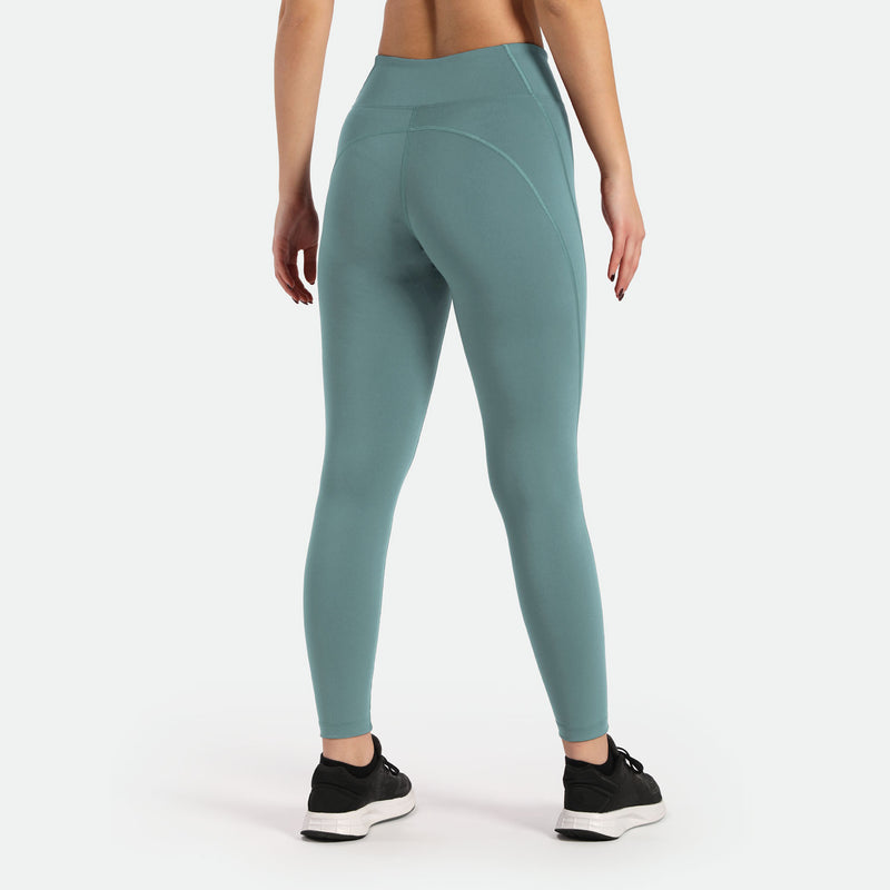 a back view for woman wearing  legging goblin  blue  with shoes black ,plus the background is light grey 