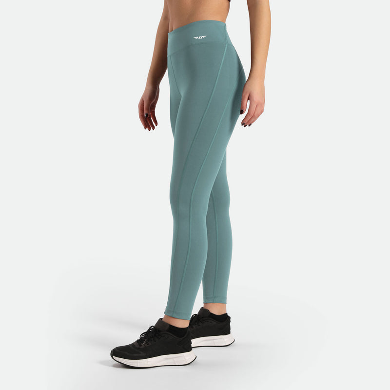 a fit woman stand at right and wearing legging green with shoes black ,plus the background is light grey 