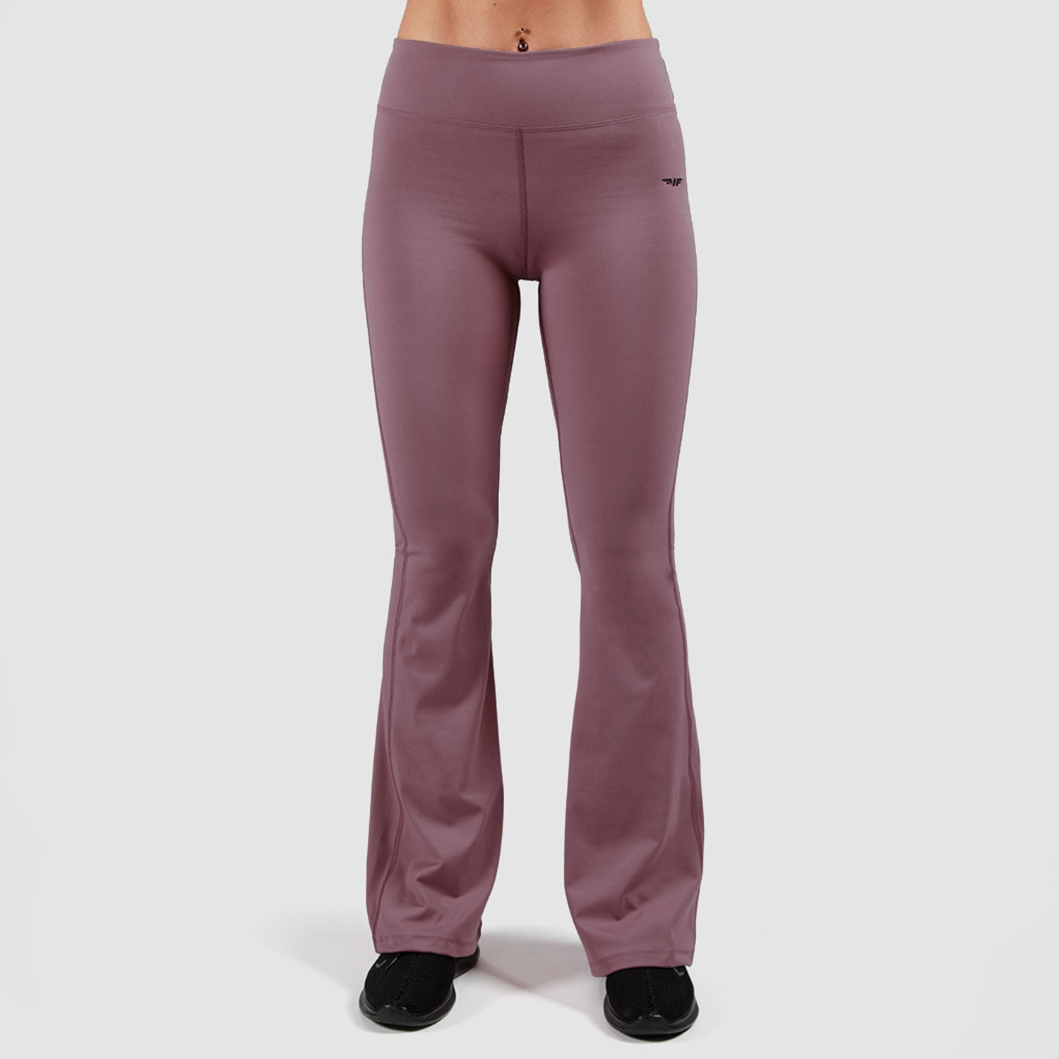 a woman wearing flared legging grapeade-purple with shoes black ,the background is light grey 