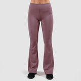 a woman wearing flared legging grapeade-purple with shoes black ,the background is light grey 