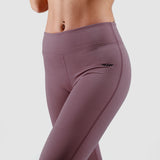 a fit woman wearing flared legging purple  with logo black ,plus the background is light grey 