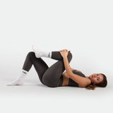 a fit woman sleep on around and wearing matching set quite shade grey ,bra and legging ,plus the socks 