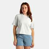 Woman wearing a white t-shirt and light blue shorts on a plain background