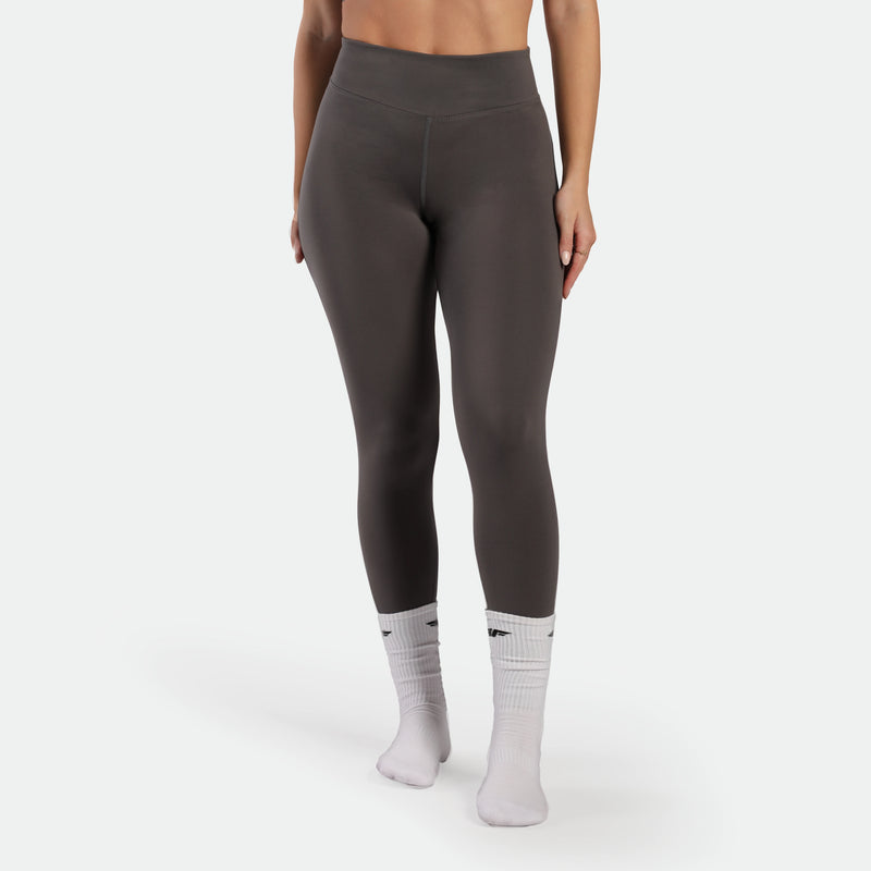 Person wearing dark gray leggings and white socks on a white background