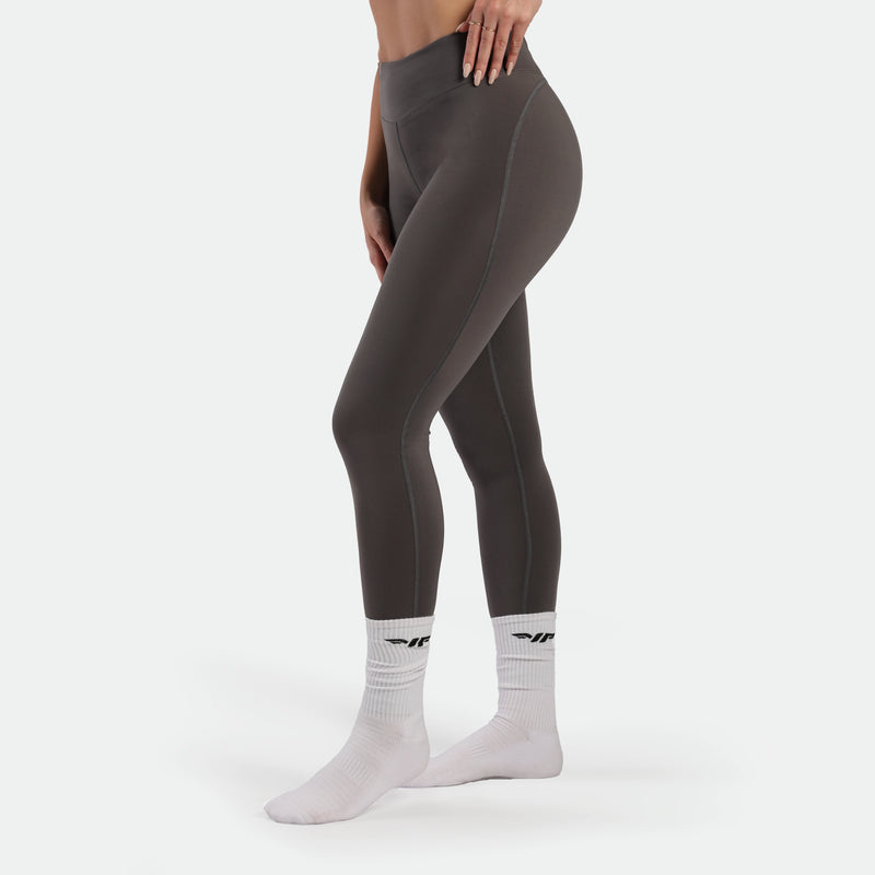 Person wearing gray leggings and white socks with a logo on a white background