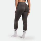 Person wearing dark gray leggings with a logo on a white background