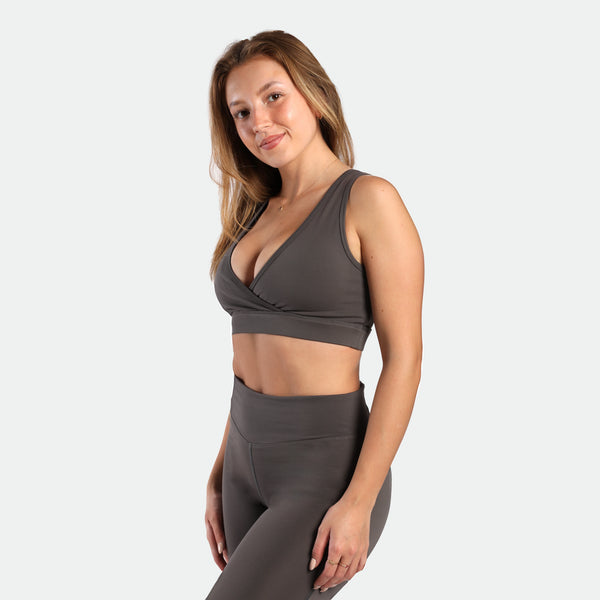 a fit woman stand at right and wearing bra and legging quite shade grey 