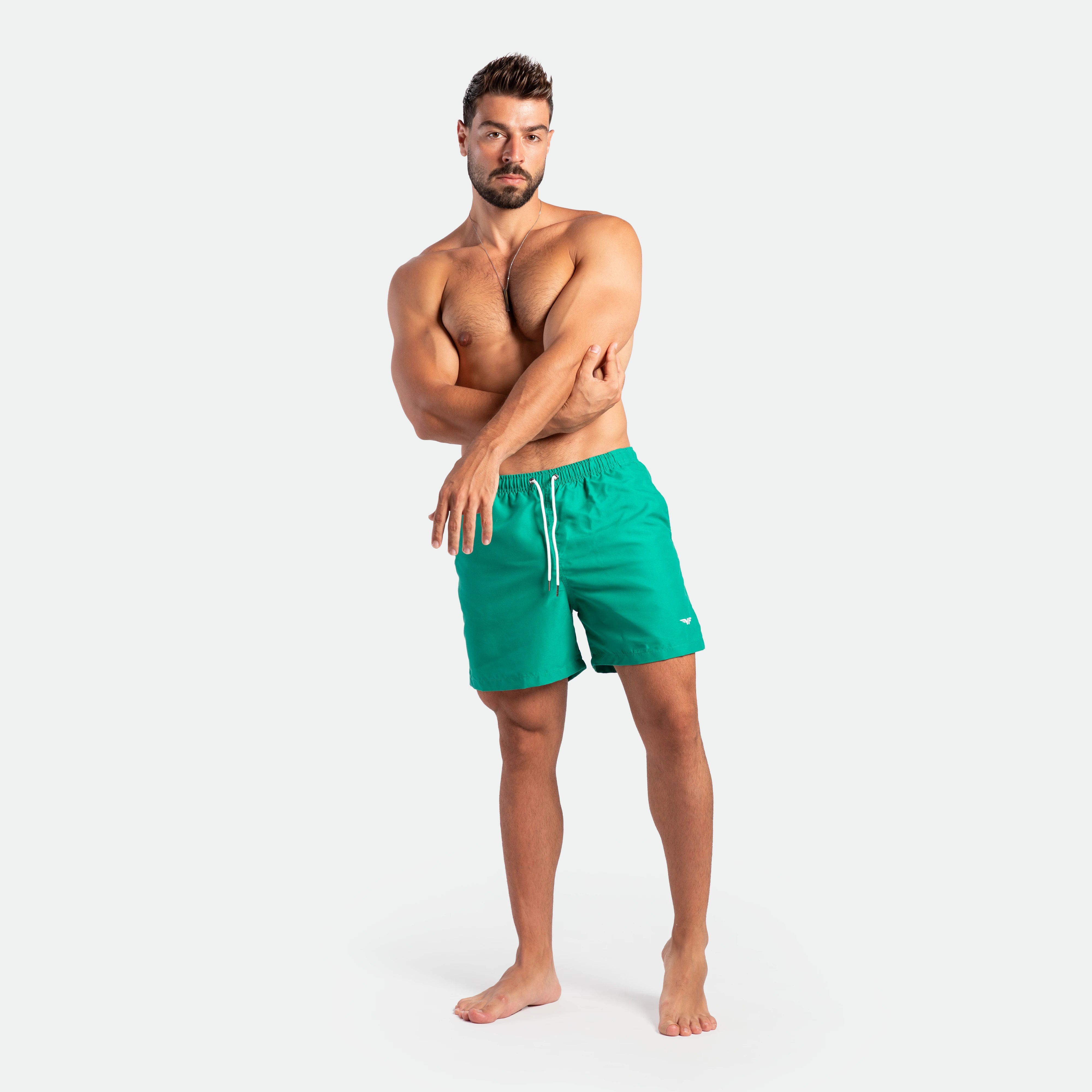 a fit man stand at right and wearing short green lake 
