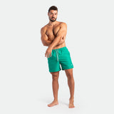 a fit man stand at right and wearing short green lake 