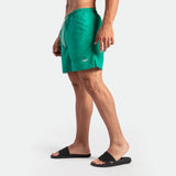 a fit man stand at right and wearing short green lake 