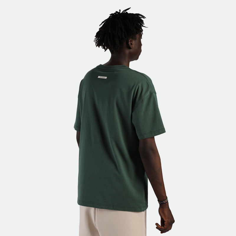 a back view for fit man wearing t-shirt green  with pants  beige 