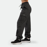 a fit woman stand at right and wearing jogger pants ebony grey with shoes black 