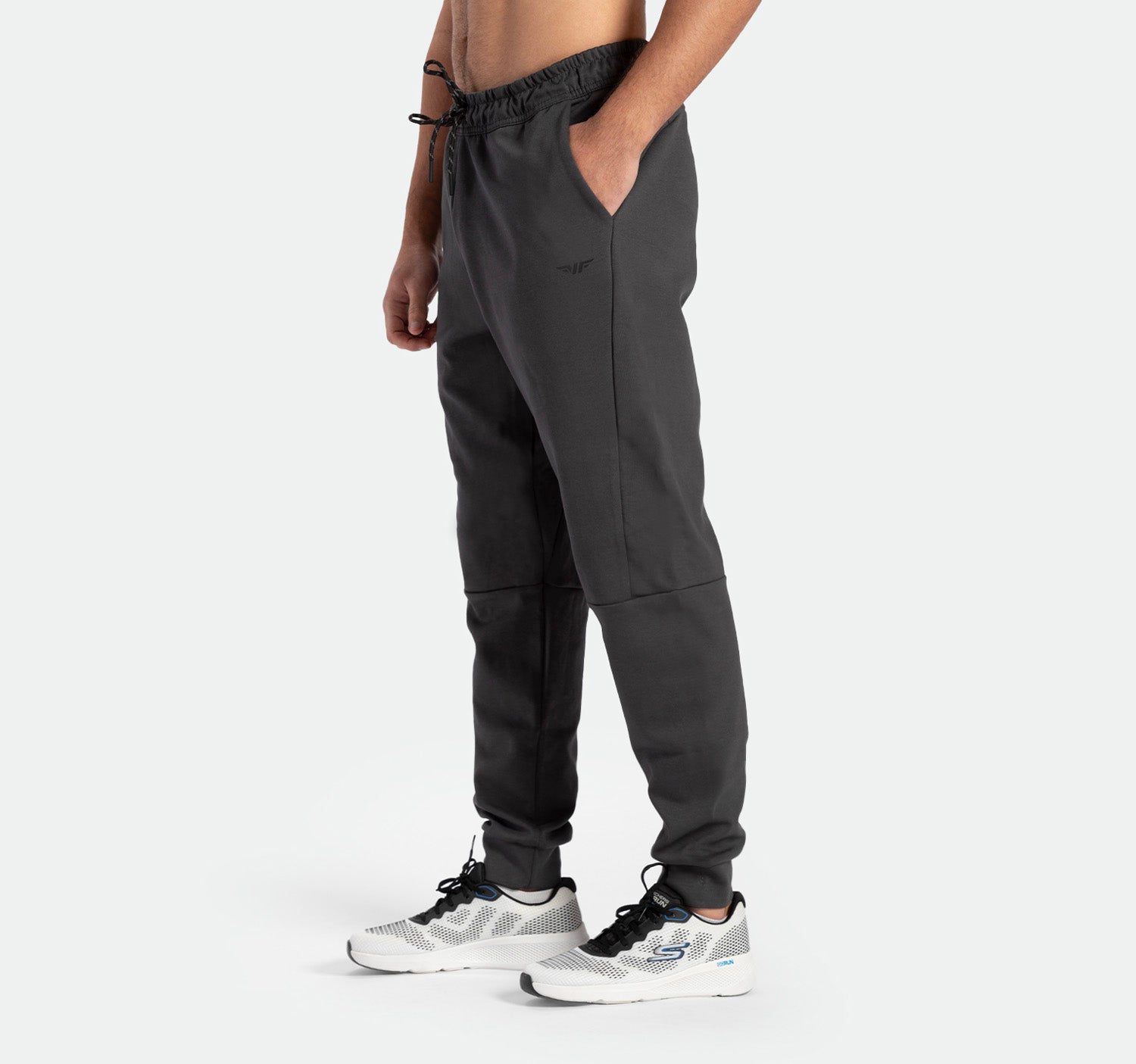 a fit man stand at right and wearing  pants grey ebony with shoes sports 