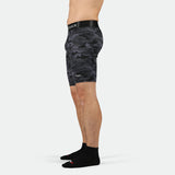 a fit man stand at right and wearing short grey toned camo with socks black 