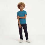 A boy posing and wearing a regular fit saxony blue camo t-shirt with the word FORCE in big on it. He is also wearing navy pants and white shoes.