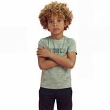 A boy posing and wearing a regular fit camo t-shirt in the color green bay with the word FORCE in big on it. He is also wearing navy pants.