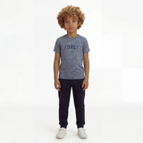 A boy posing and wearing a regular fit vintage indigo camo t-shirt with the word FORCE in big on it. He is also wearing navy pants and white shoes.