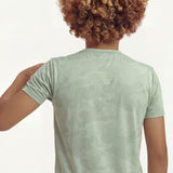 Back close-up view of a boy posing and wearing a regular fit camo t-shirt in the color green bay.