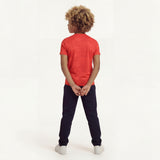 Back view of a boy posing and wearing a regular fit camo t-shirt in the color high risk red. He is also wearing navy pants and white shoes.