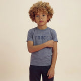 A boy posing, touching the sleeve of his t-shirt. and wearing a regular fit vintage indigo camo t-shirt with the word FORCE in big on it. He is also wearing navy pants.