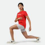 a fit woman stand with pose sport and she wearing camo red t-shirt with short grey and sneakers 