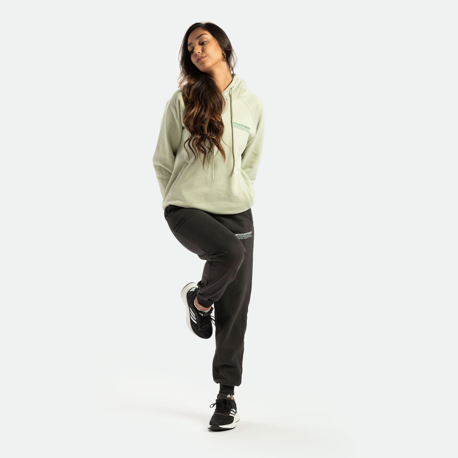 a fit woman wearing t-shirt green with pants black and sneakers 