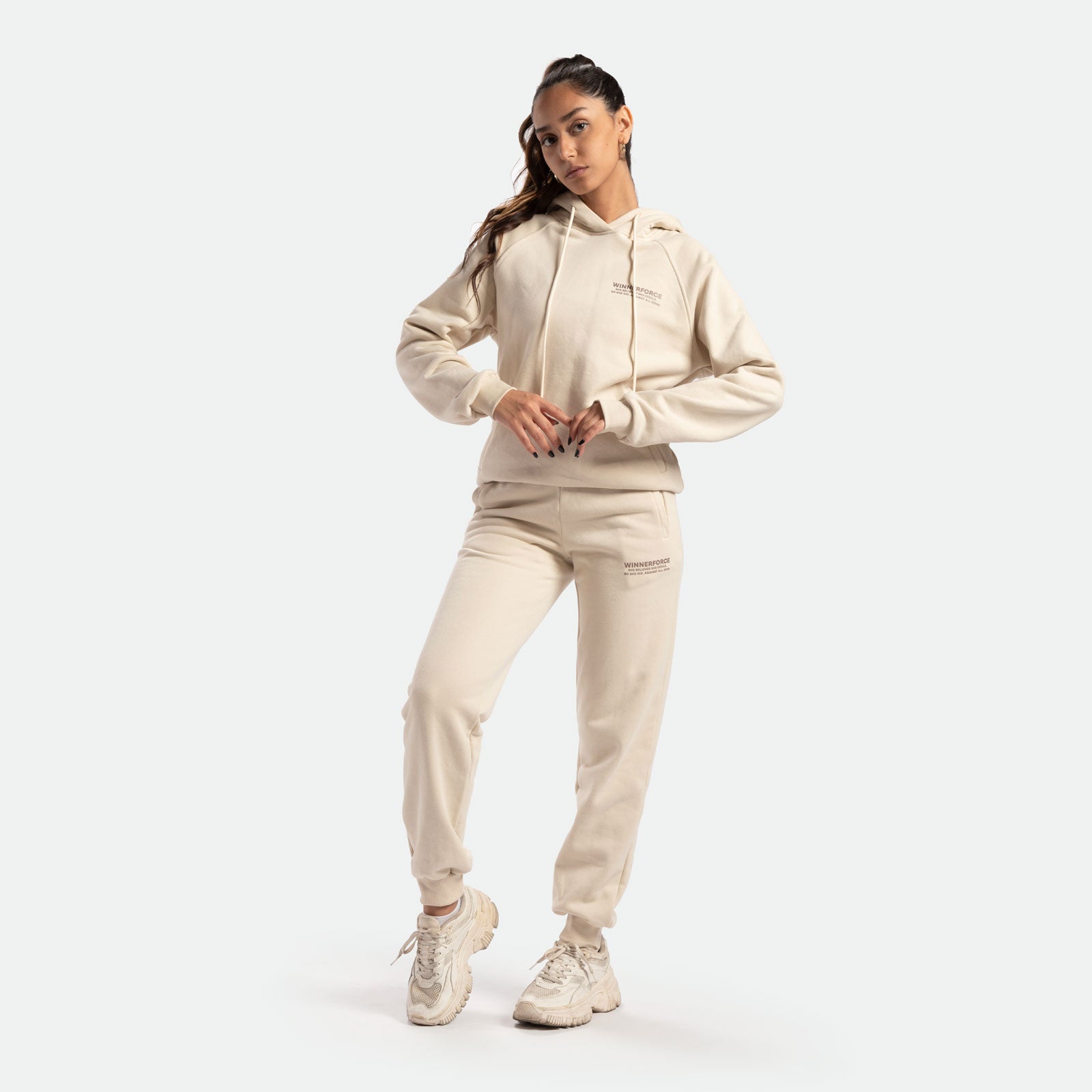 a fit woman wearing hoodie and pants beige ,plus she wearing  sneakers 