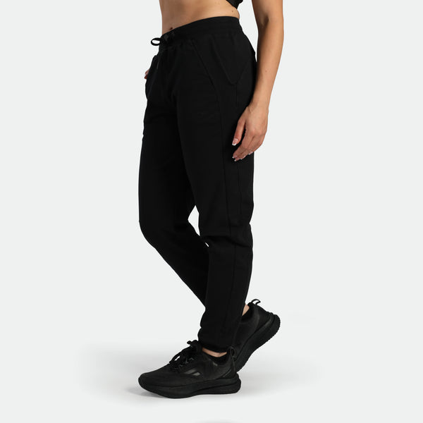a fit man stand at right and wearing jogger   pants black , plus the shoes black 