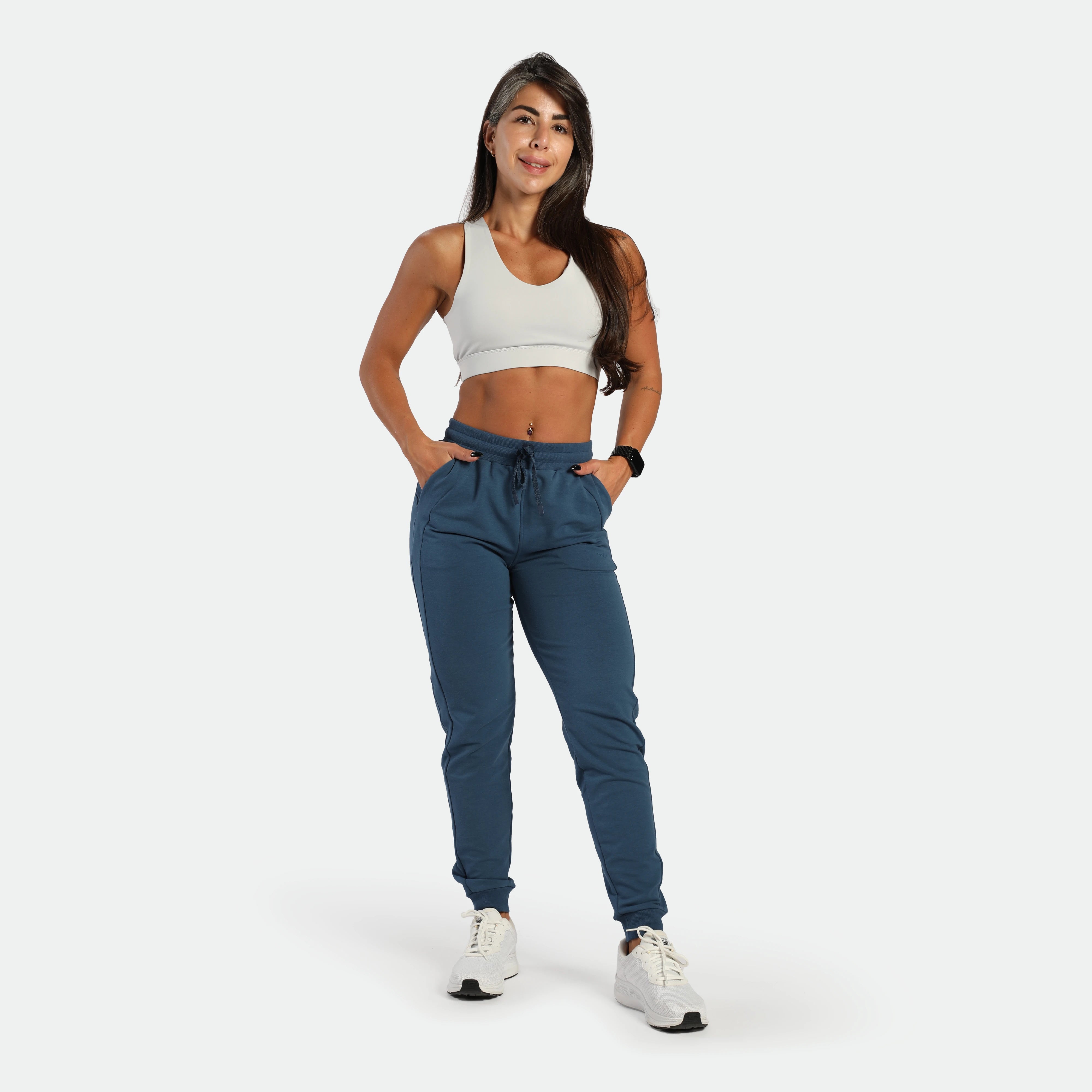 a fit woman wearing bra white and jogger pants blue 