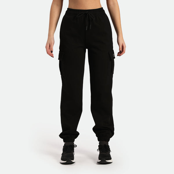 a woman wearing jogger pant with tow pocket and shoes same color is black ,plus the background is light grey 