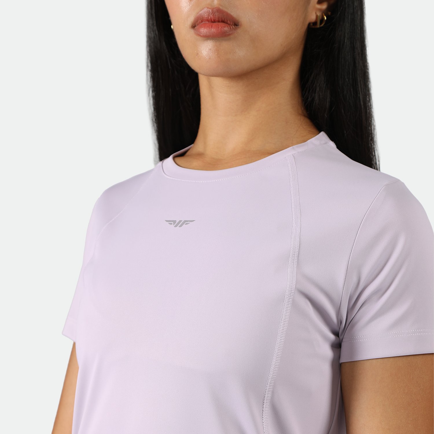 close up view for fit woman wearing   a light purple athletic t-shirt, plus he background is light grey 
