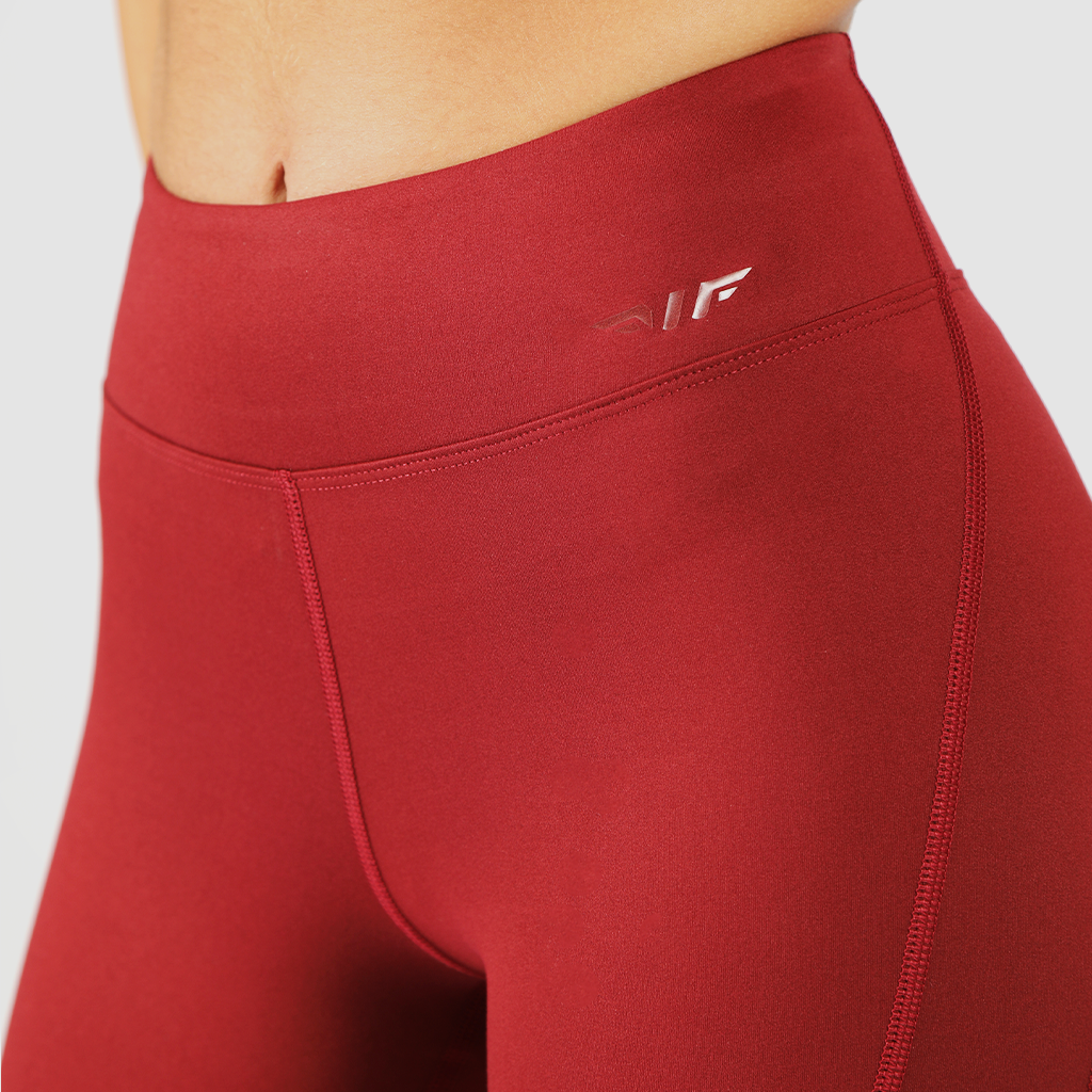 a fit woman wearing legging red  with logo same color ,the background is light grey 