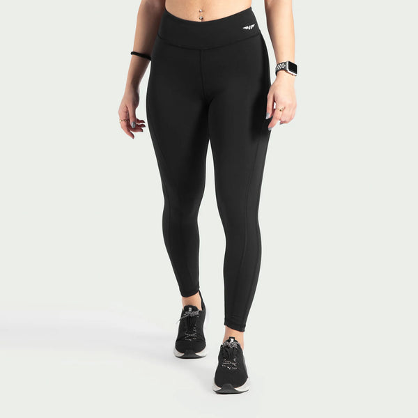 a fit woman wearing legging black  with logo  and shoes black, plus the background is light grey 