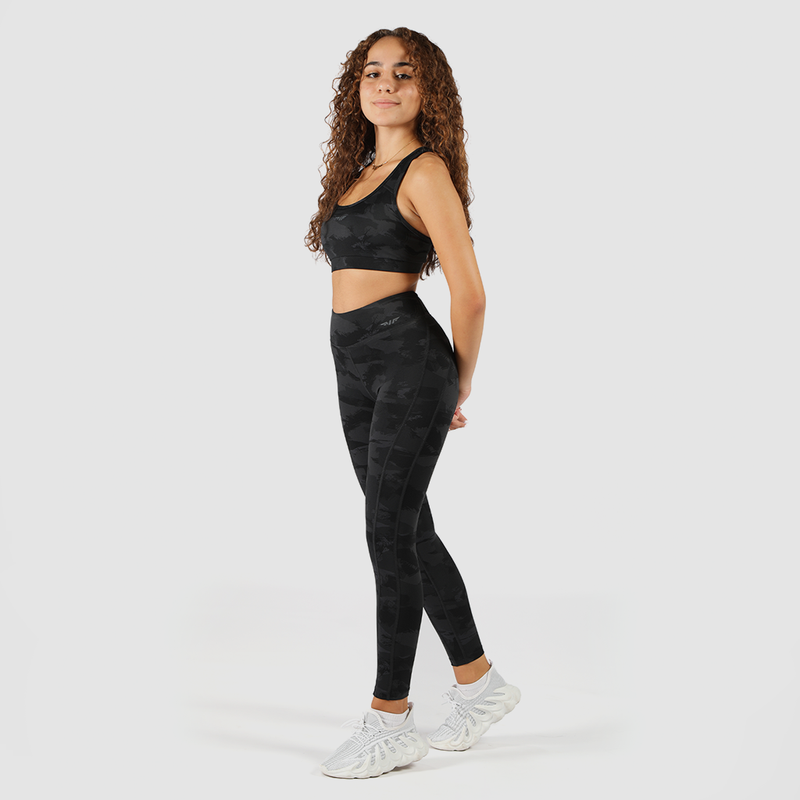 a fit woman wearing matching camo bra and legging ,same logo, plus background is light grey  