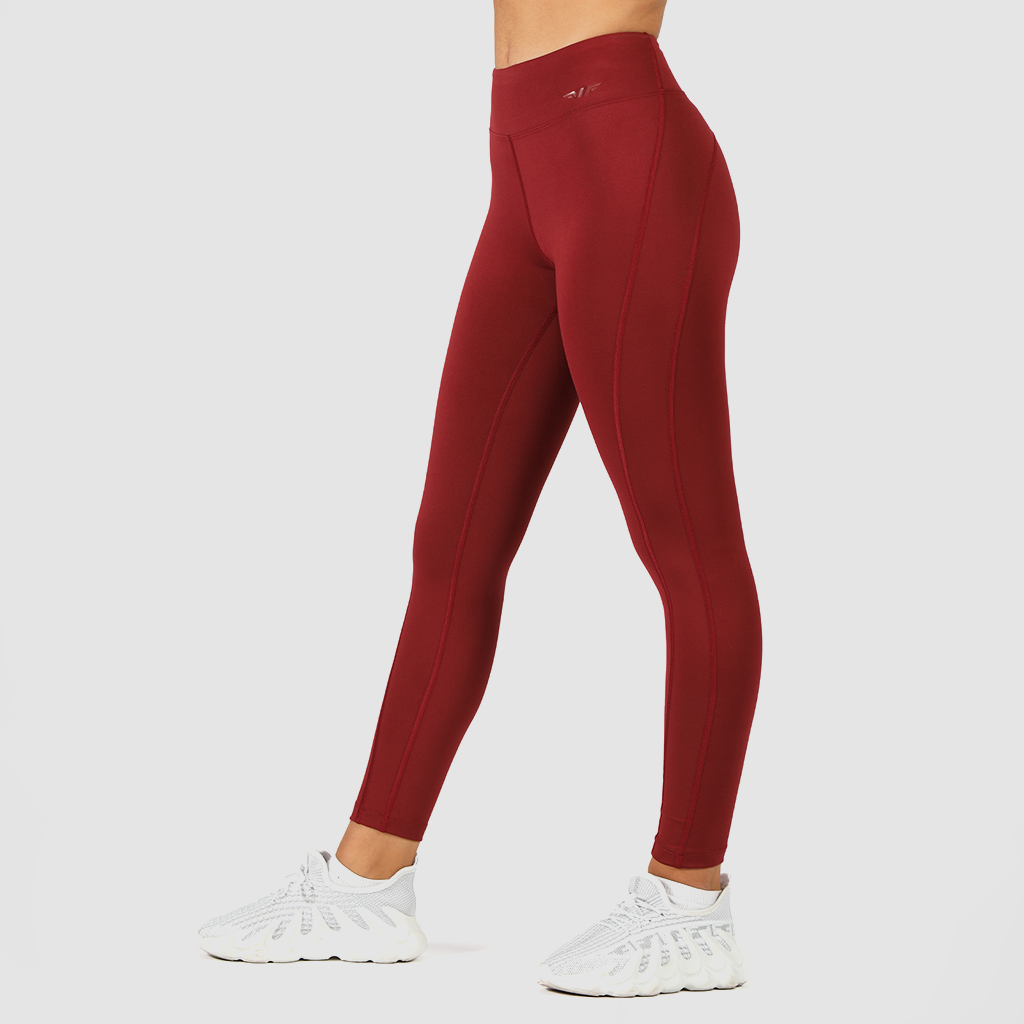 a fit woman stand at right and wearing legging red with shoes white ,the background is light grey 