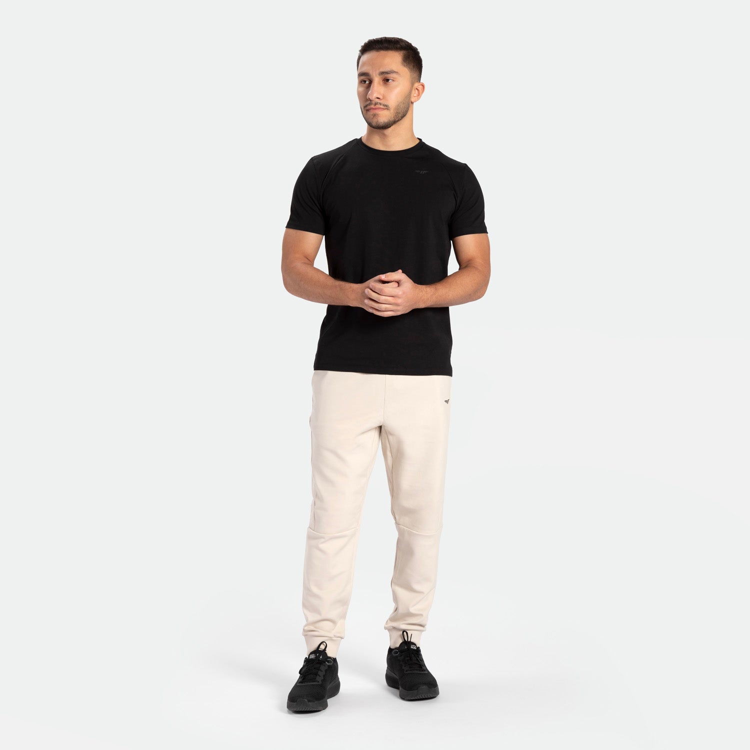 a fit man wearing t-shirt black with pants beige ,plus shoes black 