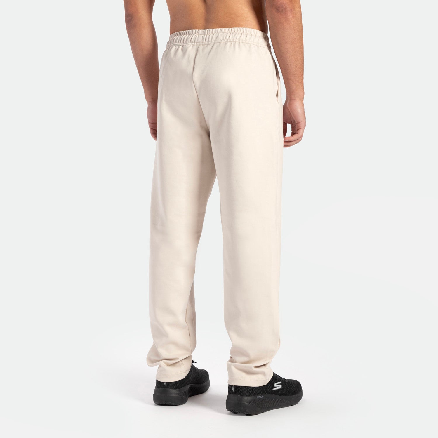 a back view for fit man wearing  pants beige with shoes back 