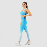 a fit woman stand at right an she wearing matching bra and legging a blue gradien ,plus the background is light grey  