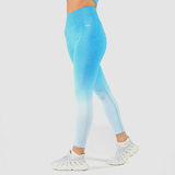 a fit woman  stand at right and she wearing legging a blue gradien with logo white ,and she wearing shoes white ,plus the background is light grey 