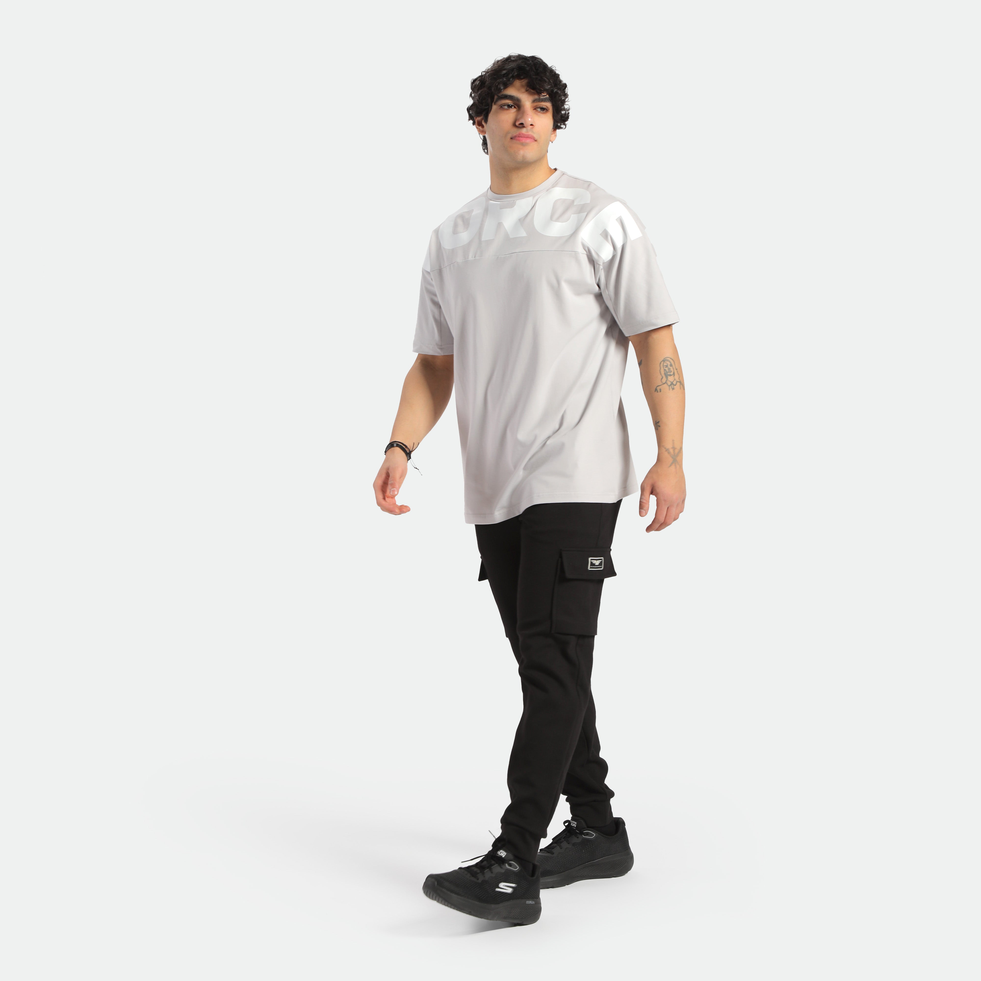 a fit man wearing t-shirt light grey with pants black ,plus shoes black 