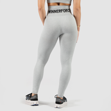 Back view of a woman wearing gray legging with a large and black logo with high waist, wearing shoes, and the background is light gray