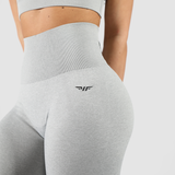 a fit woman wearing matching  bra and legging grey with logo black ,the background is light grey 