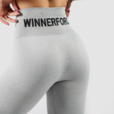 Back view of a woman wearing   legging grey with a large logo black, the background is light grey 