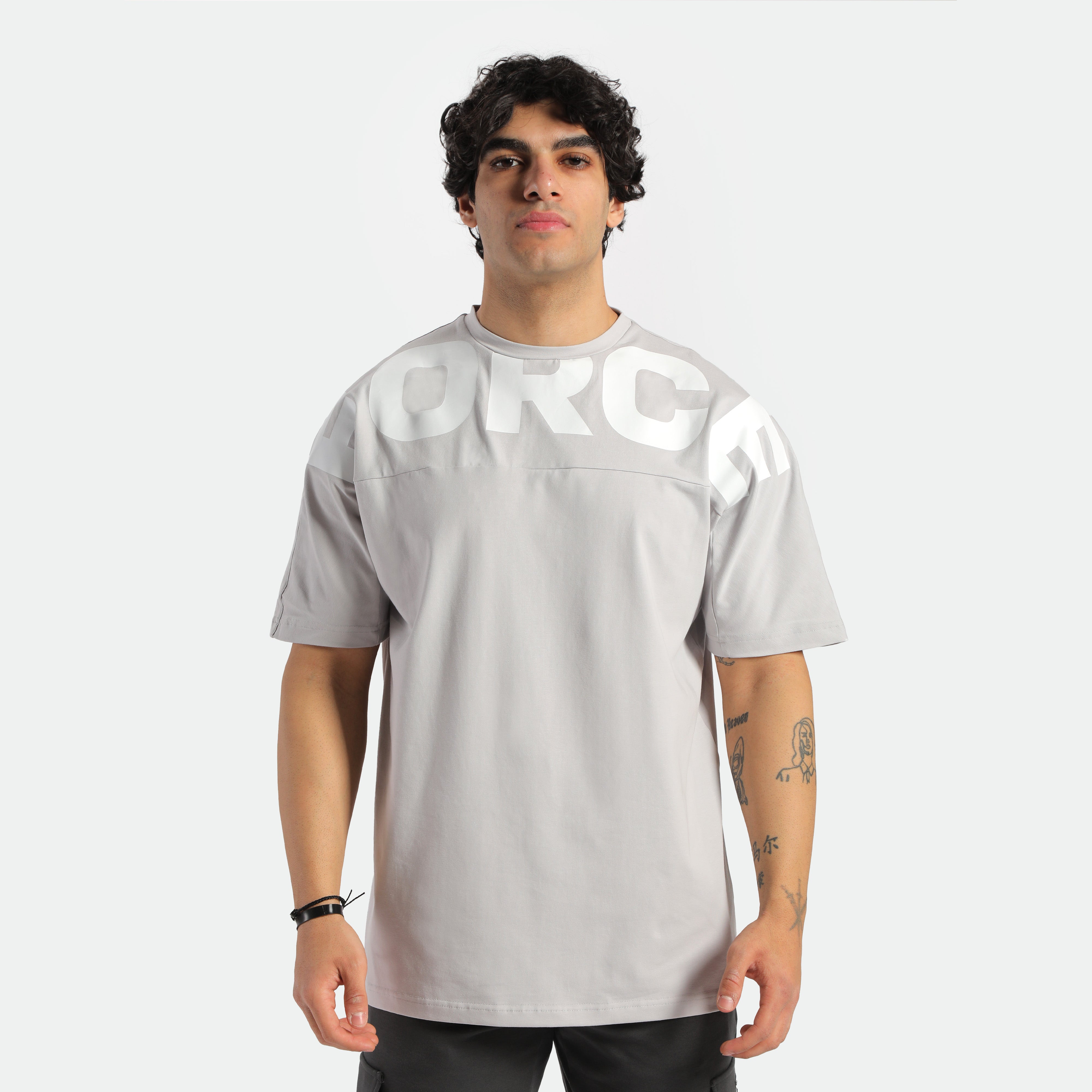 a fit man look at camera ,he wearing t-shirt light grey with logo and pants black 