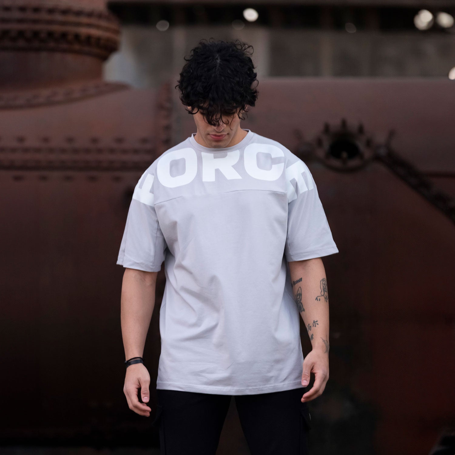a fit man wearing t-shirt  light grey with logo and pants back 