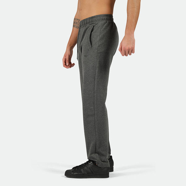 a fit man stand at right and  he  wearing pants marl dark grey with shoes black 