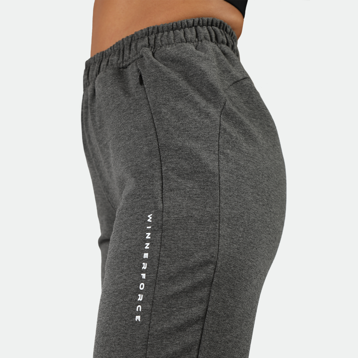 a close up view for for logo on pockets of  dark grey jogger pants ,plus the background is light grey 