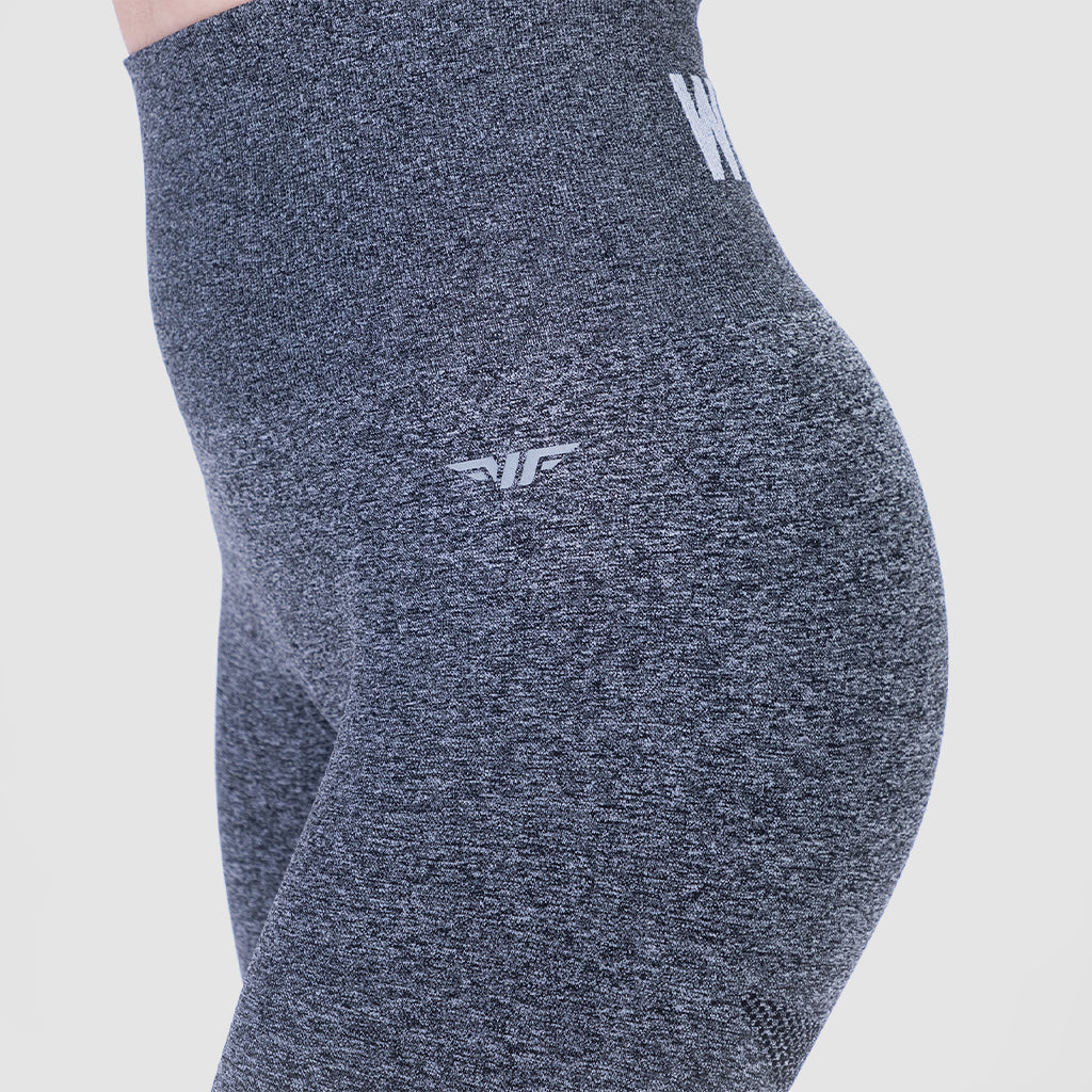 a fit woman wearing legging grey with logo , and the background is light grey 