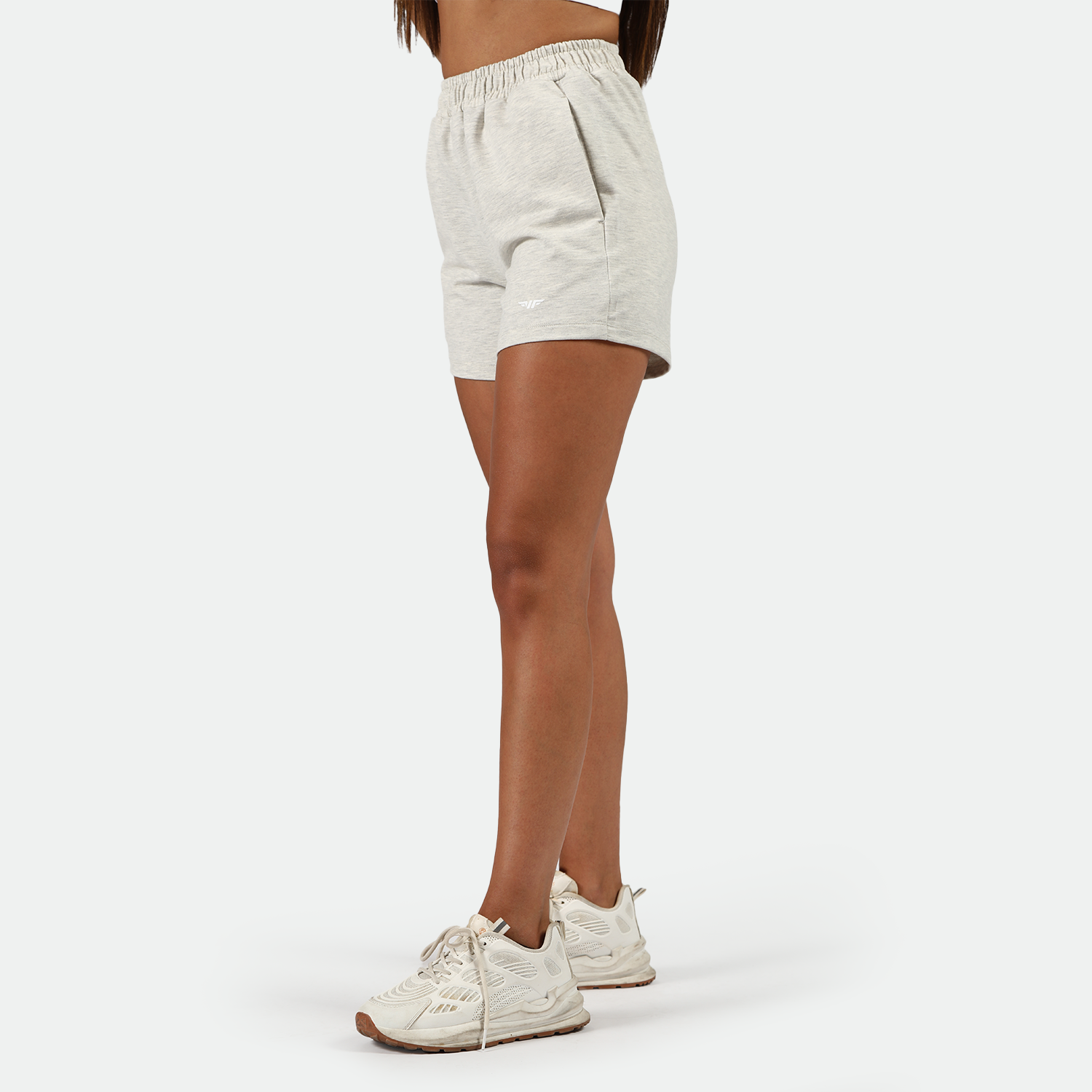 a fit woman stand at right and  wearing marl light grey  with shoes white ,plus the background is light grey 
